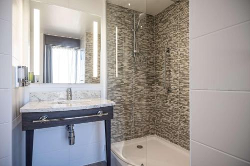 a bathroom with a sink and a shower and a tub at Hampton By Hilton Stockton On Tees in Stockton-on-Tees