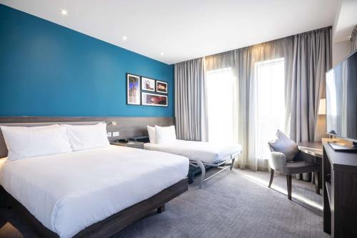 a hotel room with two beds and a blue wall at Hampton By Hilton Stockton On Tees in Stockton-on-Tees