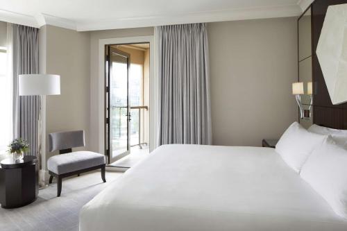 a bedroom with a large white bed and a chair at Waldorf Astoria Atlanta Buckhead in Atlanta