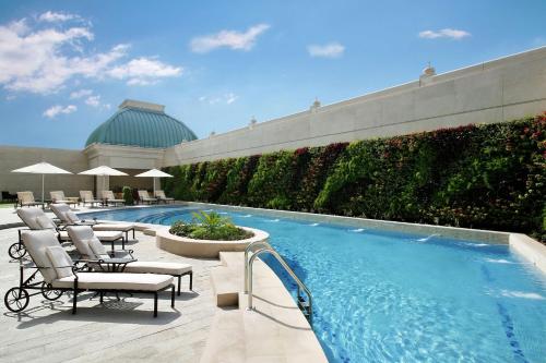 a swimming pool with lounge chairs and a resort at Habtoor Palace Dubai, LXR Hotels & Resorts in Dubai