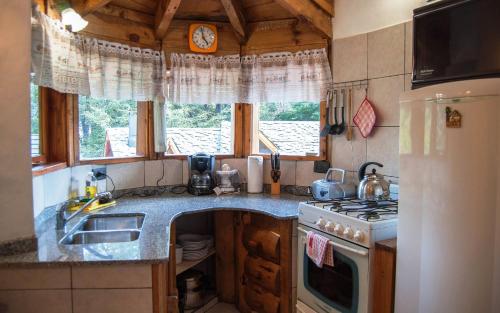 eine Küche mit einer Spüle und einem Herd Top-Backofen in der Unterkunft Cabañas Lelikelen in Villa La Angostura