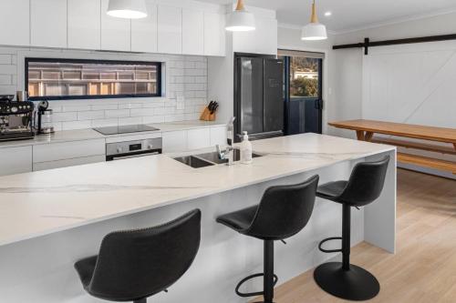 a kitchen with a counter with four chairs at it at Decked out on Leo in Waihi Beach