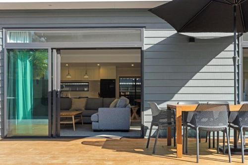a house with a patio with a table and chairs at Decked out on Leo in Waihi Beach