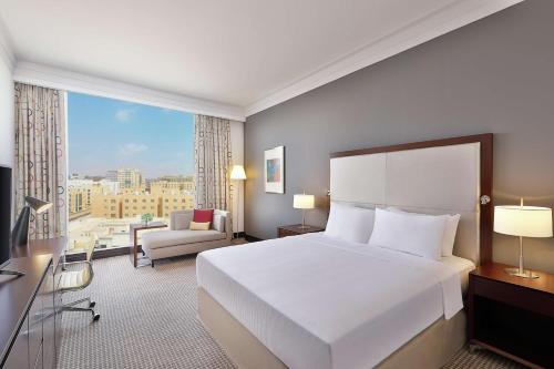 Doubletree By Hilton Doha - Al Sadd في الدوحة: غرفة نوم بسرير ابيض كبير ونافذة