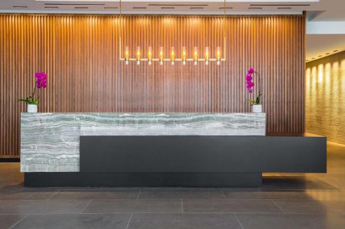 a reception desk in a lobby with purple plants at C. Baldwin, Curio Collection by Hilton in Houston