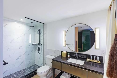 a bathroom with a sink and a shower with a mirror at C. Baldwin, Curio Collection by Hilton in Houston