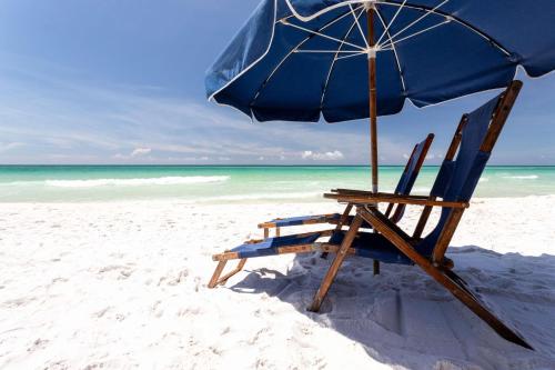a blue beach chair with an umbrella on the beach at Hilton Garden Inn Destin Miramar Beach, Fl in Destin