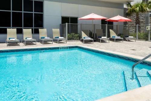 a swimming pool with chairs and umbrellas at Hilton Garden Inn Destin Miramar Beach, Fl in Destin