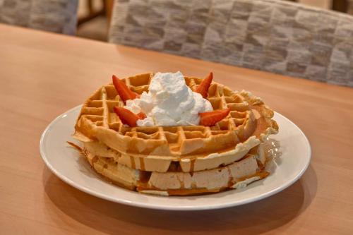 a waffle with whipped cream on a plate on a table at Hilton Garden Inn Destin Miramar Beach, Fl in Destin