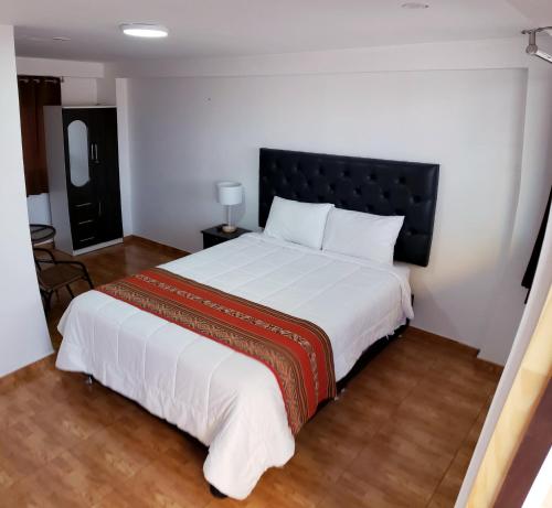 um quarto com uma grande cama branca e uma cabeceira preta em Cusco de mis Sueños Hostal - II em Cusco