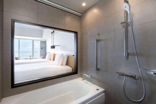 a bathroom with a bath tub and a large mirror at Hilton Okinawa Sesoko Resort in Motobu