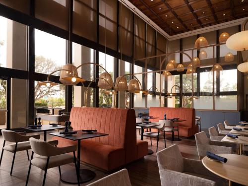 a restaurant with tables and chairs and large windows at Hotel Fera Anaheim, a DoubleTree by Hilton Hotel in Anaheim