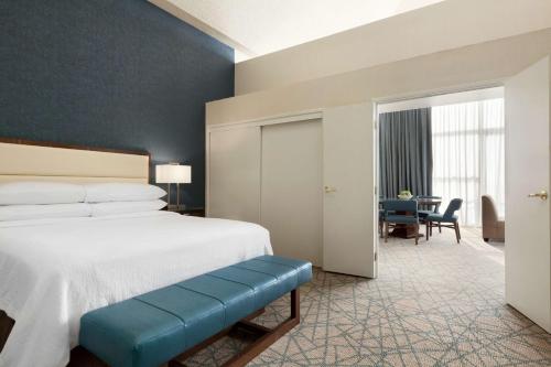 a bedroom with a bed with a blue bench in it at Embassy Suites by Hilton Brea - North Orange County in Brea