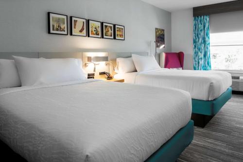 a hotel room with two beds and a chair at Hilton Garden Inn Ocala Downtown, Fl in Ocala