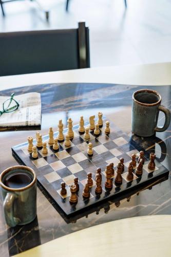 a chess board with chess pieces on a table with two cups at The Cassara Carlsbad, Tapestry Collection By Hilton in Carlsbad