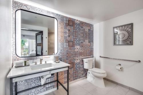 ein Badezimmer mit einem Waschbecken, einem WC und einem Spiegel in der Unterkunft The Cassara Carlsbad, Tapestry Collection By Hilton in Carlsbad