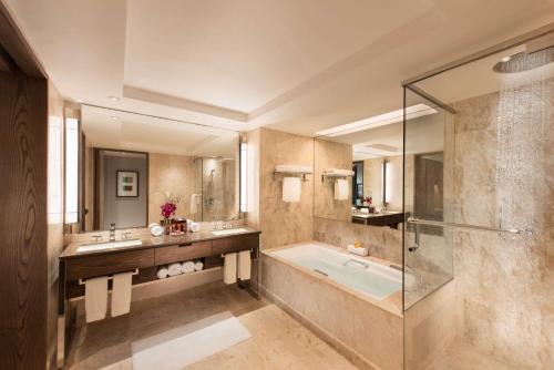 a bathroom with a tub and two sinks and a shower at Conrad Centennial Singapore in Singapore