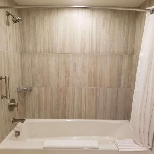 a bathroom with a white tub and a shower at The Cassara Carlsbad, Tapestry Collection By Hilton in Carlsbad