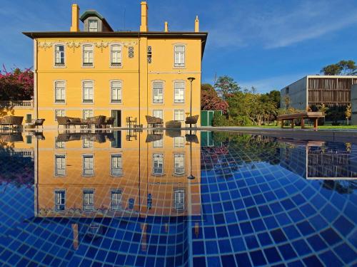 a building with its reflection in a pool of water at Boeira Garden Hotel Porto Gaia, Curio Collection by Hilton in Vila Nova de Gaia
