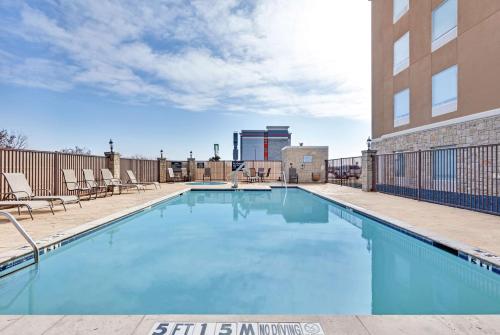 a swimming pool with chairs and a building at Hampton Inn & Suites Abilene I-20 in Abilene