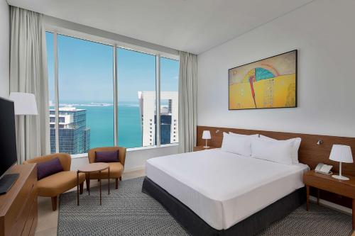 a hotel room with a bed and a large window at Aleph Doha Residences, Curio Collection By Hilton in Doha