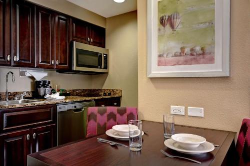 a kitchen with a wooden table with plates on it at Homewood Suites by Hilton Albuquerque Airport in Albuquerque