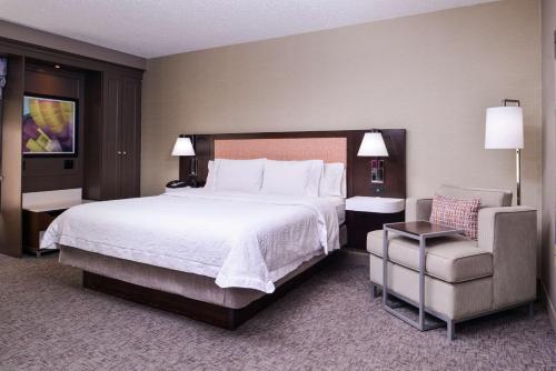 a hotel room with a large bed and a chair at Hampton Inn Albuquerque - University/Midtown in Albuquerque
