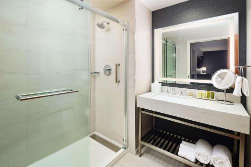 a bathroom with a shower and a sink and a mirror at Hilton Charlotte Airport Hotel in Charlotte