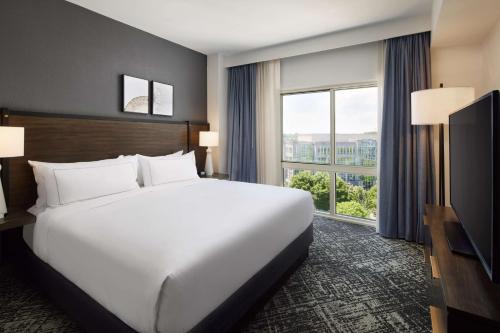 a large white bed in a hotel room with a large window at Hilton Charlotte Airport Hotel in Charlotte