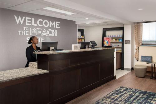 a woman standing at a welcome to the beach office at Hampton Inn & Suites Alpharetta-Windward in Alpharetta