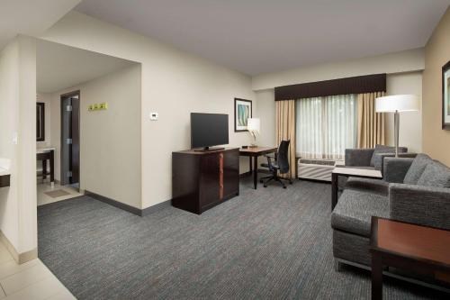 a hotel room with a couch and a desk with a television at Hampton Inn & Suites Alpharetta-Windward in Alpharetta