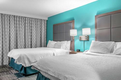 2 camas en una habitación de hotel con paredes azules en Hampton Inn Adel, en Adel