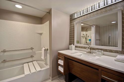 a bathroom with a tub and a sink and a mirror at Home2 Suites by Hilton Nashville Vanderbilt, TN in Nashville