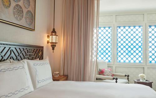 a bedroom with a bed and a chair and a window at Hilton Salwa Beach Resort and Villas in Abū Samrah
