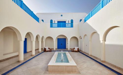 a courtyard with a pool in the middle of a building at Hilton Salwa Beach Resort and Villas in Abū Samrah