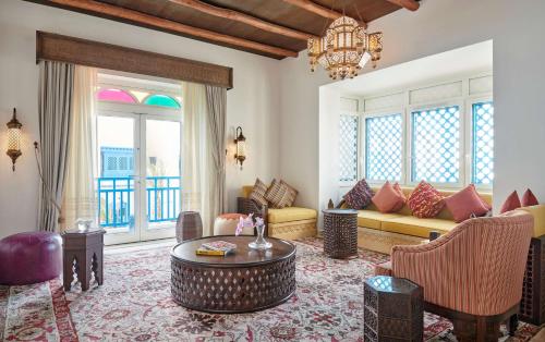 a living room filled with furniture and a chandelier at Hilton Salwa Beach Resort and Villas in Abū Samrah