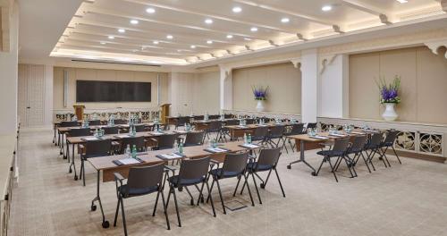 a large room with tables and chairs and a projection screen at Hilton Salwa Beach Resort and Villas in Abū Samrah