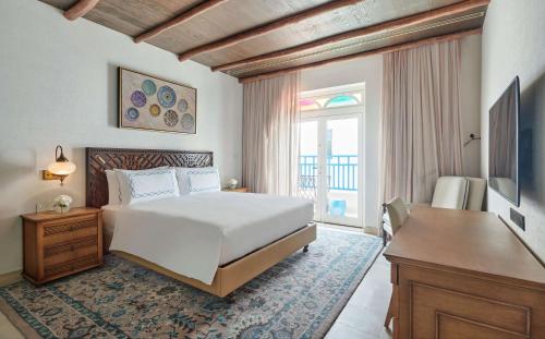 a bedroom with a bed and a desk and a television at Hilton Salwa Beach Resort and Villas in Abū Samrah