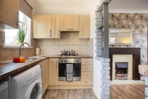 a kitchen with a washer and dryer next to a fireplace at Rawmarsh House, Rotherham for contractors & Families, off-road parking, high speed wifi in Rotherham