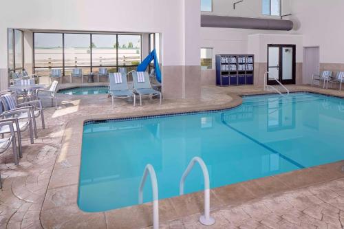 a large pool in a hotel with chairs and tables at Embassy Suites by Hilton Boston Marlborough in Marlborough