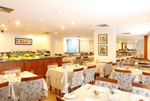 un restaurante con mesas y sillas blancas y un buffet en Flat Live Lodge, en São Paulo
