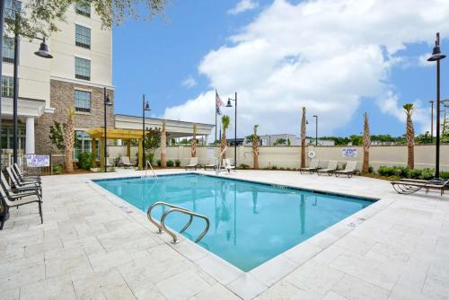 a pool at a hotel with chairs and a building at Hampton Inn & Suites Charleston Airport in Charleston