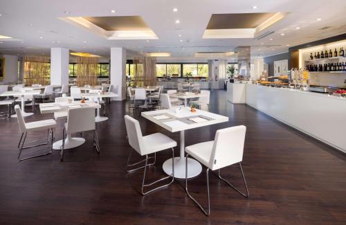 un restaurante con mesas y sillas blancas y un bar en Best Western Plus Tower Hotel Bologna, en Bolonia