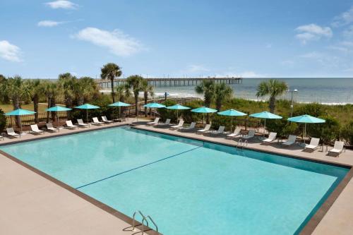 a pool with chairs and umbrellas and the beach at DoubleTree Resort by Hilton Myrtle Beach Oceanfront in Myrtle Beach