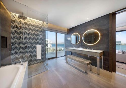 a bathroom with a tub and a sink and mirror at Hilton Abu Dhabi Yas Island in Abu Dhabi