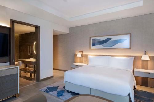 a bedroom with a bed and a desk and a television at Hilton Abu Dhabi Yas Island in Abu Dhabi