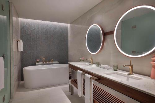 a bathroom with a tub and a sink and a mirror at Hilton Abu Dhabi Yas Island in Abu Dhabi