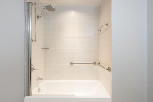 a bathroom with a shower with a white tub at Courtyard by Marriott New York JFK Airport in Queens