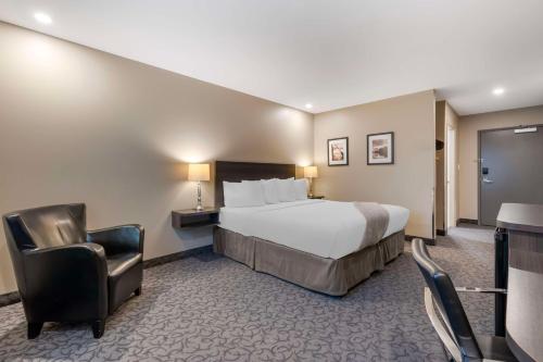 Pokój hotelowy z łóżkiem i krzesłem w obiekcie Villa Inn & Suites - SureStay Collection by Best Western w Hearst
