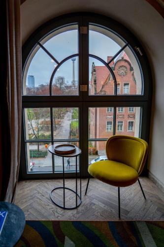 a room with a yellow chair and a large window at Telegraphenamt in Berlin